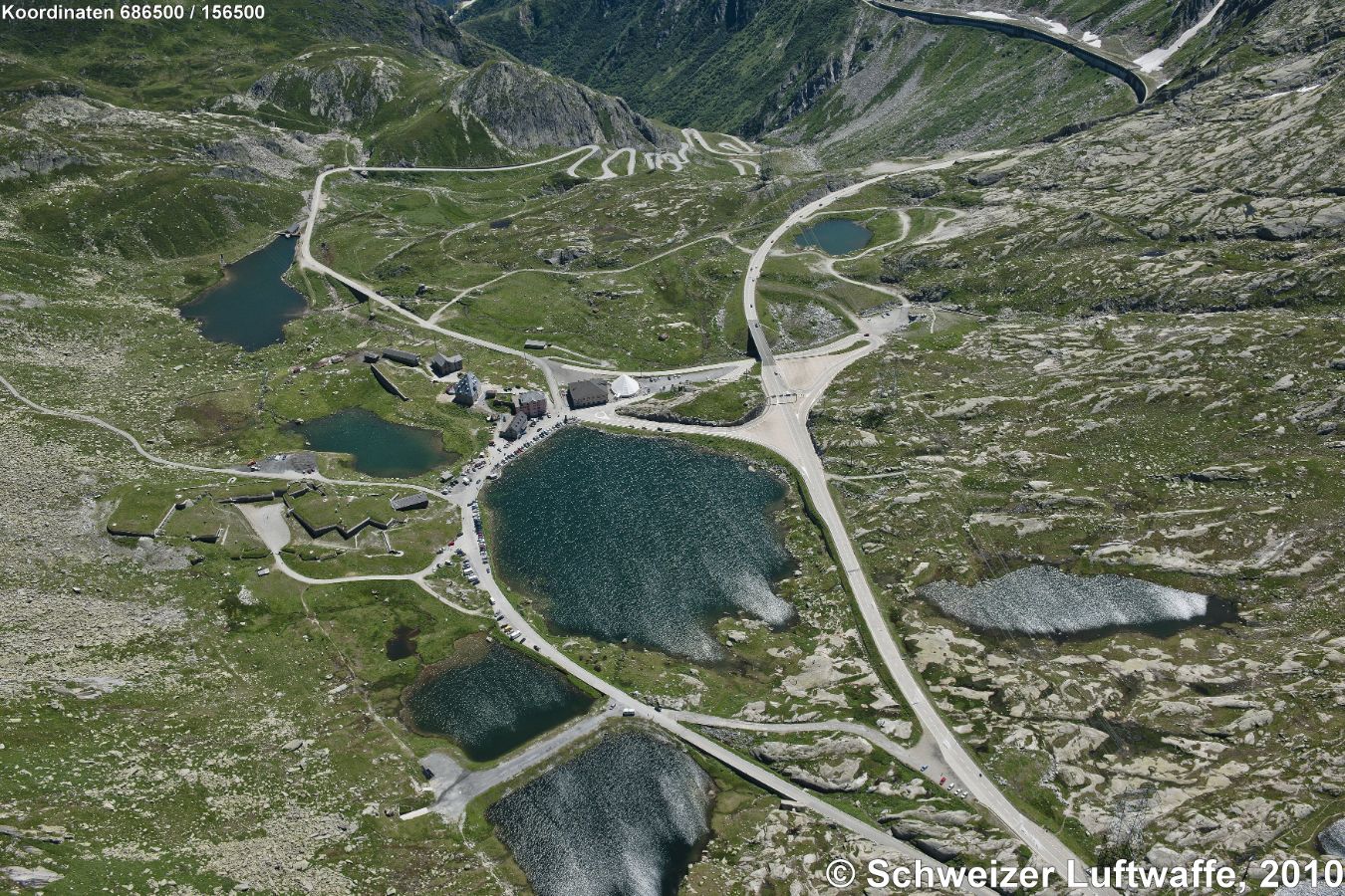 Ospizio San Gottardo, 2091 m.ü.M. (Position: 2'686'600.83, 1'156'692.44) Bildmitte: Lago della Piazza; Alte Passstrasse der Tremola im Hintergrund; Anstieg gegen linke Seite: zum Monte Prosa; gegen rechte Seite: zum Piz Fibbia.